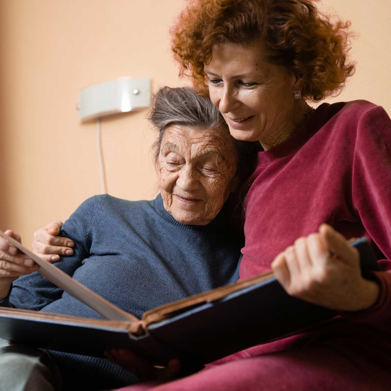 A home hospice patient flips through a photo album with her daughter.
