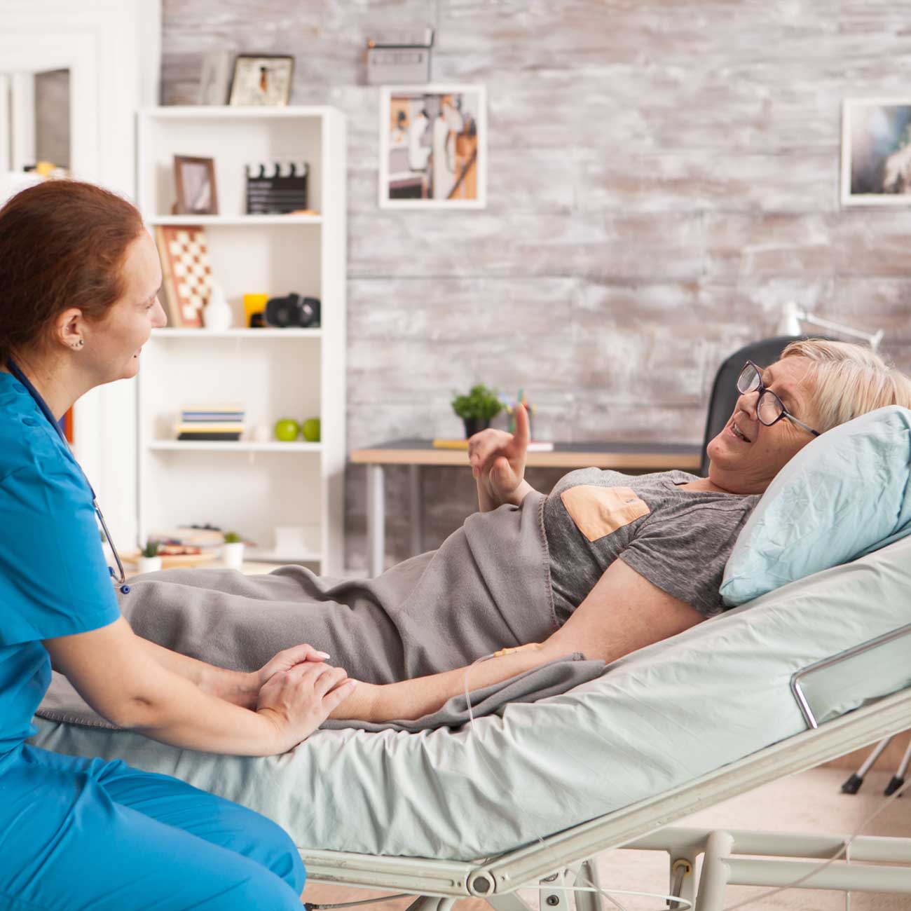 Hospice nurse with a patient on a hospital bed at home.